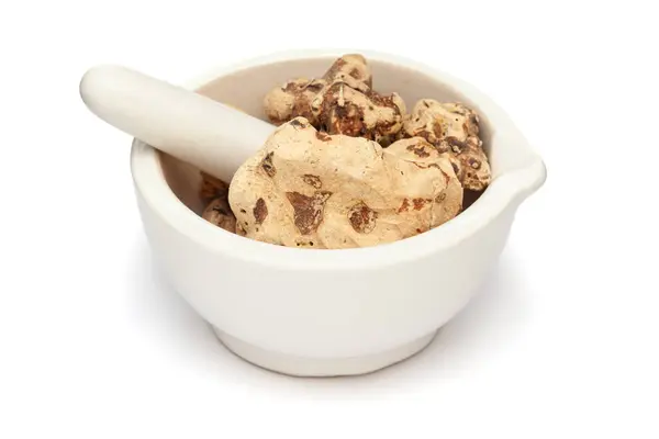 stock image Close-up of Dry Organic Chobchini (Smilax china), in white ceramic mortar and pestle, isolated on a white background.