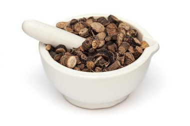 Beyaz bir zemin üzerinde izole edilmiş seramik havan ve tokmak, kuru organik altın göz otu veya siyah musli (Curculigo orchioides) bitkisi yakın plan.