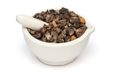 Beyaz bir zemin üzerinde izole edilmiş beyaz seramik havan ve tokmak, Kuru Organik Bektaşi (Phyllanthus emblica) veya Amla yakın plan.