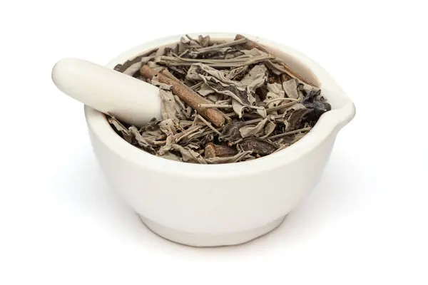 stock image Close-up of Dry Organic Nirgundi (Vitex negundo) leaves, in white ceramic mortar and pestle, isolated on a white background.