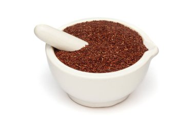 Beyaz bir zemin üzerinde izole edilmiş beyaz seramik havan ve tokmak, kuru organik uyku bitki veya Lajvanti (Mimosa pudica) tohumları yakın plan.