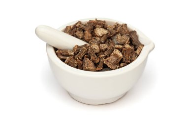 Beyaz bir zemin üzerinde izole edilmiş seramik havan ve tokmak, kuru organik Gulvel veya Giloy (Tinospora cordifolia) bitkisi yakın plan.