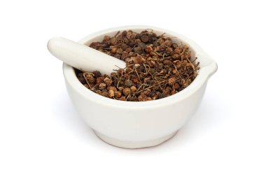 Beyaz bir zemin üzerinde izole edilmiş beyaz seramik havan ve tokmak, Kuru Organik Siyah İtüzümü veya Makoy (Solanum nigrum) meyvesi yakın plan.