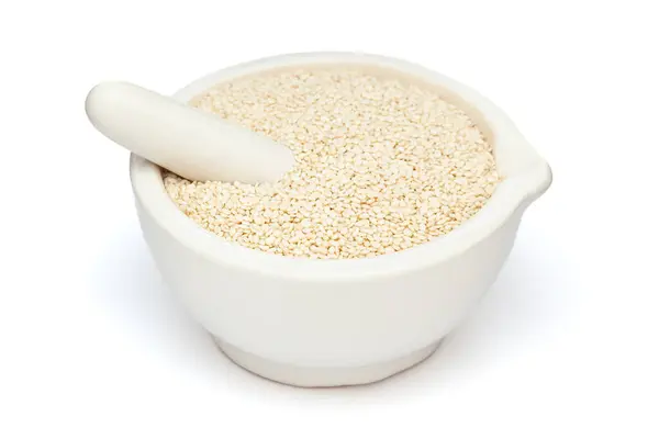 stock image Close-up of Dry Organic White Sesame seeds (Sesamum indicum) or Til, in white ceramic mortar and pestle, isolated on a white background.