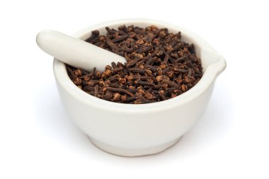 Kuru organik karanfil (Syzygium aromaticum) ya da beyaz bir zemin üzerinde beyaz seramik havan ve tokmak uzun Hindistan yapımı yakın plan.