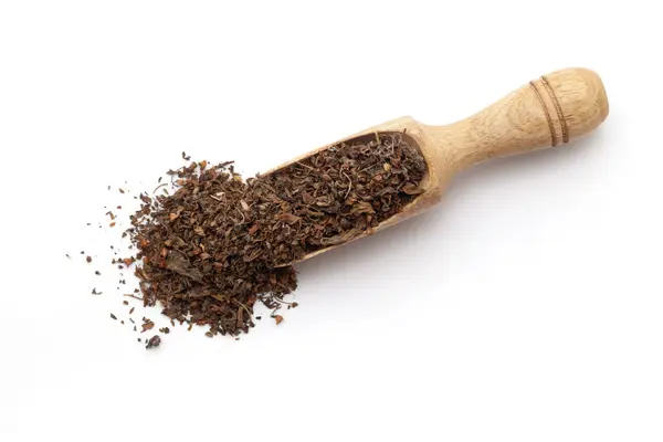 stock image Top view of a wooden scoop filled with dry Organic Green Holy Basil or  Rama Tulsi (Ocimum Sanctum) leaves. Isolated on a white background.