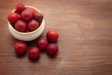 Beyaz arka planda seramik bir kasede taze kiraz eriği (Prunus cerasifera) meyvelerinin ön görüntüsü.