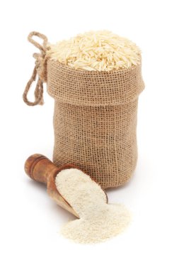 Organik beyaz pirinç (Oryza sativa), bir jüt torba içinde ve pirinç unu kepçesinde, beyaz arka planda izole edilmiş..