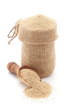 Kuru Organik Beyaz Haşhaş tohumlarının (Papaver somniferum) yakın plan çekimi, bir jüt torba içinde ve beyaz arka planda izole edilmiş bir kepçe üzerinde.