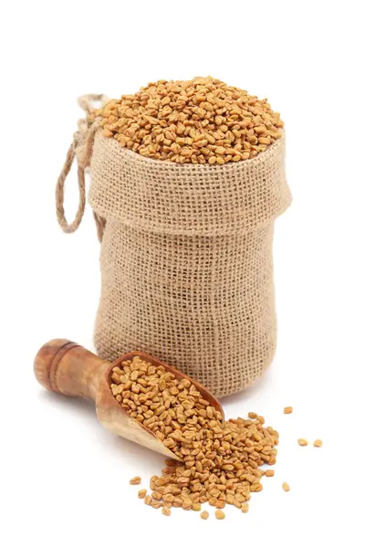 stock image Close-up of Organic Fenugreek seeds (Trigonella foenum-graecum), in a jute bag and on a scoop, Isolated on a white background.