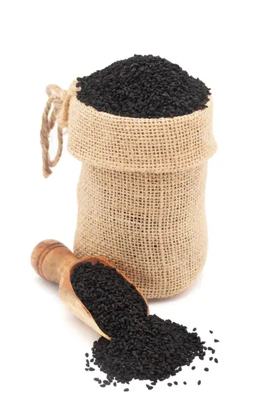 stock image Close-up of Organic Black Cumin  (Nigella sativa) or kalonji, in a jute bag and on a scoop, Isolated on a white background.