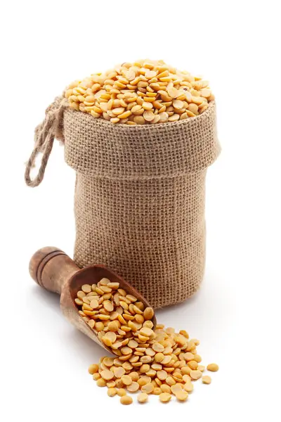 stock image Close-up of organic split Pigeon Peas (Cajanus cajan), Arhar dal or split yellow dal, in a jute bag and on a scoop, isolated on a white background.