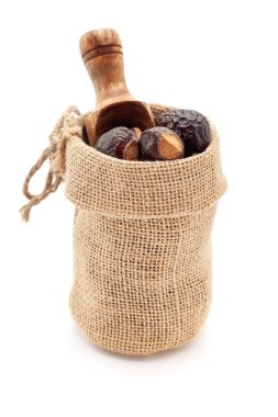 Close-up of Organic Soapnuts or Reetha (Sapindus mukorossi) berries, in a jute bag with a scoop, Isolated on a white background. clipart