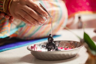 Hintli kadın Krishna Janmashtami festivali sırasında Hindu tanrısı Krishna 'nın üzerine' Ganga Jal 'dökerek snan ritüeli gerçekleştiriyor..