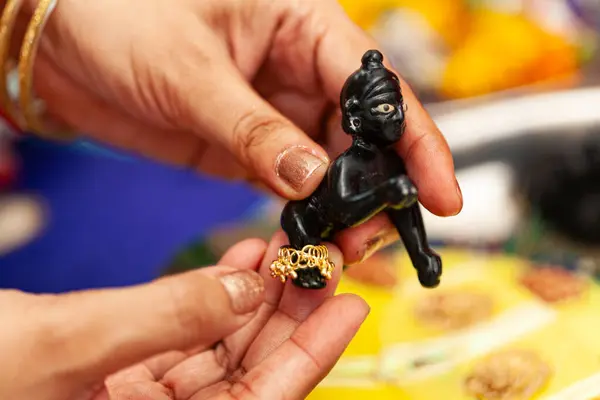 stock image An Indian woman placed an anklet on (Laddu Gopal), a Hindu god 'Krishna', after performing a ceremonial bath during the Krishna Janmashtami festival.