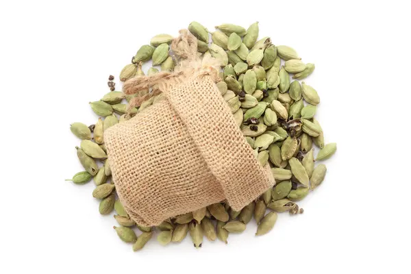 stock image Close-up of organic Cardamom (Elettaria cardamomum) in a jute bag on a heap of cardamom, isolated on a white background.