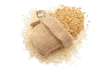 Organik Rice Bran (Oryza sativa) ya da Dhaan 'ın beyaz arka planda izole edilmiş pirinç yığını üzerinde bir jüt torba içinde yakın plan fotoğrafı..