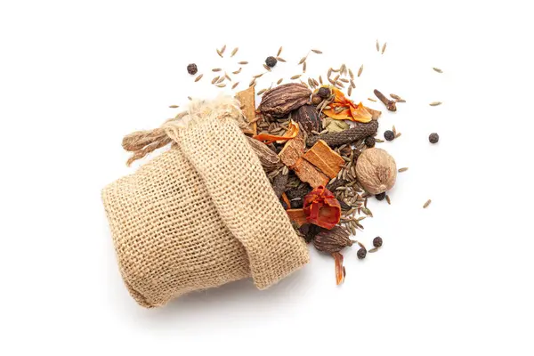 stock image Close-up of Organic warming spices or whole Garam Masala, spilled out from a laying jute bag. Isolated on a white background.