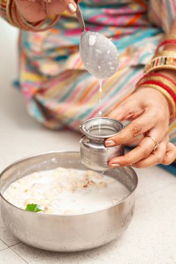 Hintli bir kadın, 'Krishna Janmashtami' vesilesiyle prasad dağıtımına hazırlanan panchamrit 'i lotaya boşaltıyor..