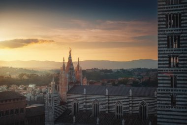 Siena Cathedral or Duomo and bell tower side view at sunset. Medieval architecture in the city of Siena, Tuscany region, Italy.