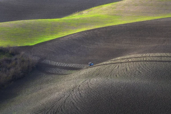 Gün batımında Tuscany 'de tarlaları süren traktör. Volterra, Pisa vilayeti. İtalya