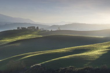 Tuscany 'de bir kışın öğleden sonra çiftlik evi ve yuvarlanan tepelerle manzara. Val d 'Orcia' nın tipik manzarası..