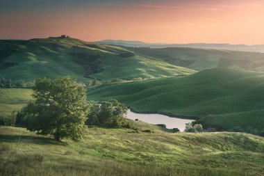 Gün batımında Girit Senesi 'nin yuvarlanan tepelerinde küçük bir göl. Monte Sante Marie, Ascanio 'da bahar manzarası, Siena ili, Toskana bölgesi, İtalya