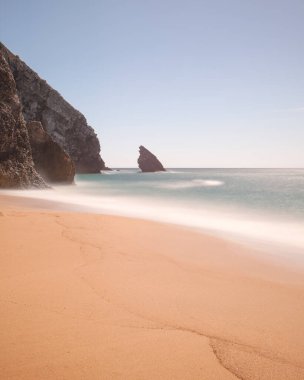 Adraga sahili manzarası ve köpekbalığı yüzgeci şeklinde kaya, Atlantik okyanusu. Uzun pozlama fotoğrafçılık, Almocageme, Sintra, Lizbon bölgesi, Portekiz