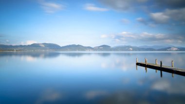 Ahşap iskele ya da gün batımında göl kenarında iskele. Uzun pozlu fotoğrafçılık. Katliam Gölü 'nün panoramik manzarası, Torre del Lago Puccini, Versilia, Toskana bölgesi, İtalya, Avrupa.
