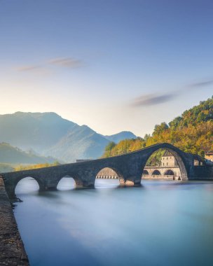 Bridge of the Devil or Ponte della Maddalena historic landmark in Garfagnana. Serchio river. Borgo a Mozzano, Lucca. Tuscany, Italy. Long Exposure in autumn. clipart