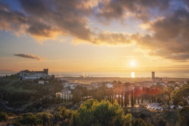 Rosignano Marittimo kasabasının, şatonun ve kilisenin manzarası. Gün batımında arkada deniz var. Toskana bölgesi, İtalya