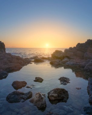 Denizin üzerinde gün batımı, sahildeki kayalar ve ön planda doğal bir havuz. Castiglioncello kıyı şeridi, Livorno ili, Toskana bölgesi, geç dönem, Avrupa