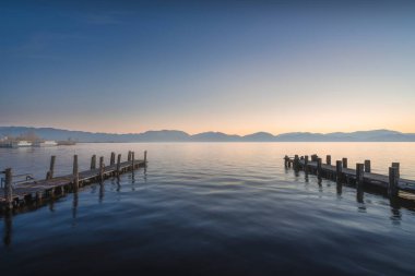 Massaciuccoli Gölü 'nde gün doğumunda iki ahşap iskele ya da jettie. Torre del Lago Puccini, Viareggio, Versilia, Lucca ili, Toskana bölgesi, İtalya