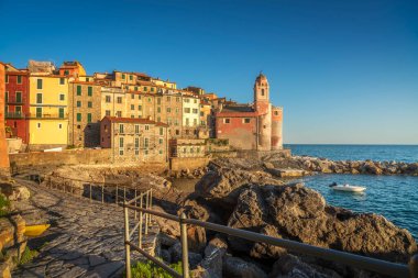 Tellaro köyü gün batımında. Kilise ve denizde küçük bir tekne. Golfo dei Poeti veya Şairler Körfezi. Liguria bölgesi, İtalya, Avrupa.