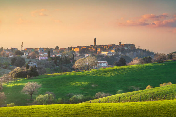 Pomarance village skyline and surrounding countryside at sunset in spring. Province of Pisa, Tuscany region, Italy