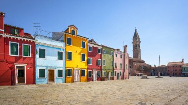 Burano adasının ana meydanı, renkli evler ve eğimli çan kulesi olan kilise. Venedik, Veneto bölgesi, İtalya
