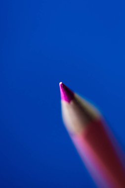 Mavi arka planda izole edilmiş pembe renkli kalem. Sığ alan derinliği