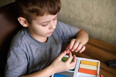 Elementary school age Caucasian child boy plays with plasticine on table, modeling clay, molds, sculpture. Cute child creating toys from play dough.