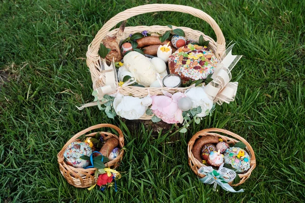 Ukrainian Easter basket filled with traditional festive dishes. Easter food, easter eggs, cheese, butter, ham, Easter bread and basket. Basket on a green grass meadow.