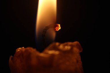 Closeup of burning candle isolated on black background. Melted Wax Candles Burning at Night.