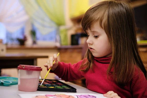 Little girl painting with water colors. Child learning different skills, creative leisure and activity for children