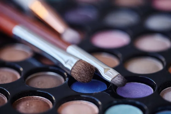 Professional makeup brushes and eyeshadow palette. Selective focus, macro shooting.