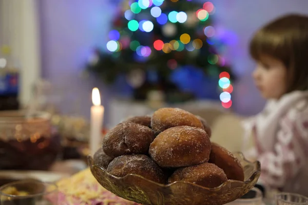 一个有甜甜圈的大盘子 在背景是一个小女孩在节庆桌上 圣诞灯 有选择的重点 — 图库照片