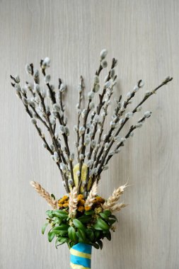 A festive willow branch adorned with flowers, wheat, and ribbons in the colors of the Ukrainian flag. Easter decorations on pussy willow