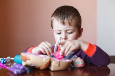 Çok renkli plastiklerle oynayan sevimli bir çocuk. Çocuk oyuncaklarla oynuyor. Olumlu, olumsuz duygular.