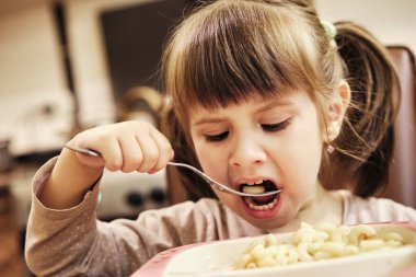 Çocuk şekilli makarna yiyor. 3.5 yaşında sevimli küçük bir kız şekilli makarna yiyor..