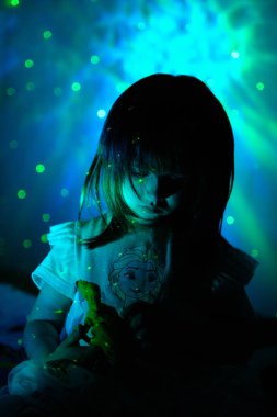 Yıldızlı ışığın parıltısında küçük bir kız. Çocuklar için Yıldız Projektör Gece Işığı