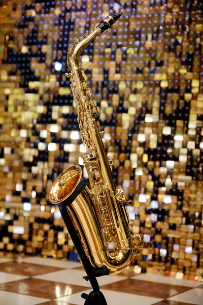 Parlak bir arka planda parlak bir saksafonun zarif görüntüsü. Müzik Enstrümanı: Bir stantta Altın Alto Saksafon. Hayat, bu müzik aletinin güzelliğini ve ustalığını yakalıyor..