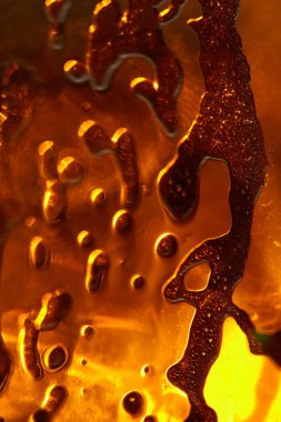 Parlak turuncu renkleri ve organik şekilleri ön plana çıkaran makro çekim. Akışkan Desenli Soyut Kehribar Cam Doku.