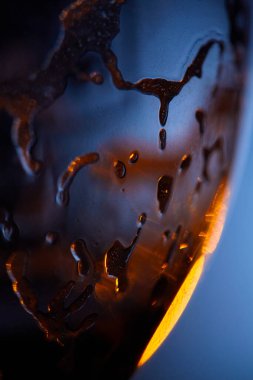 Su damlalarının soyut yakın plan çekimi ve yüzeydeki sıvı, altın ışığın ve serin mavi tonların bir oyununu yakalıyor. Soyut Sıvı: Altın Işık ve Mavi Yansımalar.